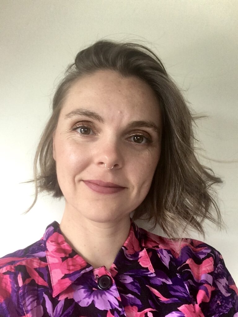 Picture of a woman with short brown hair in a pink floral shirt.